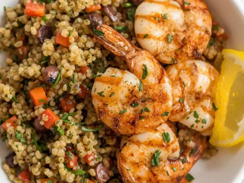 Lemon dill grilled shrimp served alongside fluffy quinoa on a plate.