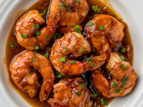 A serving of turkey-wrapped shrimp with a glossy brown sugar glaze on a plate.