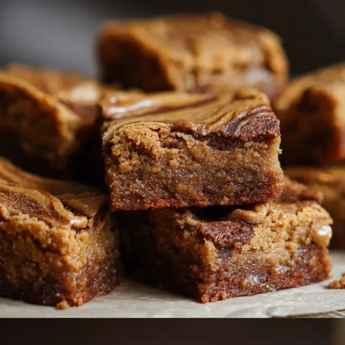 Several Biscoff blondies arranged on a serving plate, showcasing their soft texture.