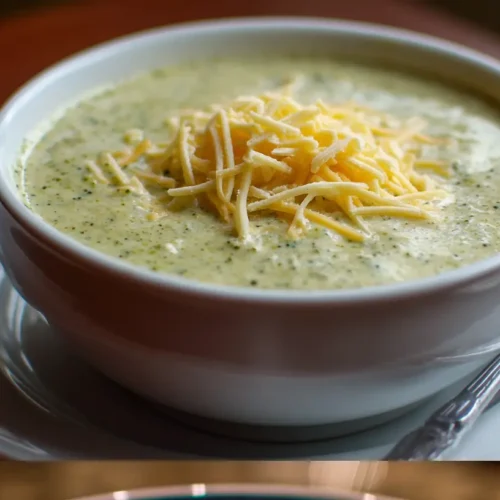 A steaming bowl of creamy broccoli cheese soup, garnished with fresh broccoli florets.