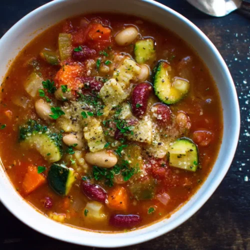 A steaming bowl of hearty Minestrone Soup with fresh vegetables