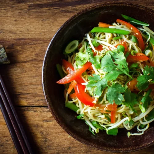 A vibrant Asian Noodle Salad with Ginger-Lime Dressing in a ceramic bowl.