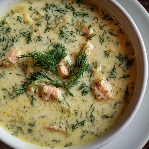 A bowl of creamy dill salmon soup garnished with fresh dill sprigs.