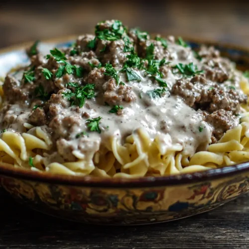 A bowl of creamy ground beef stroganoff, garnished with fresh parsley.