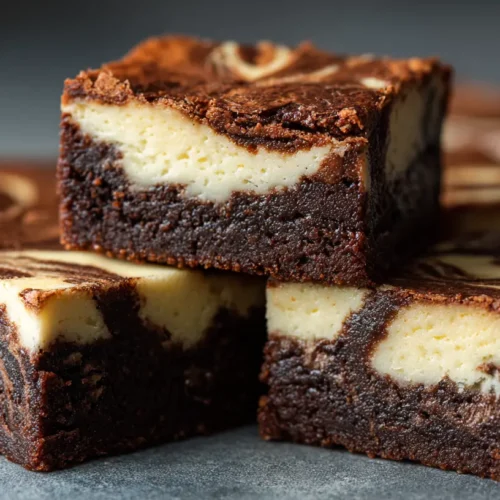 A close-up of freshly baked cheesecake brownies with a visible swirl pattern.