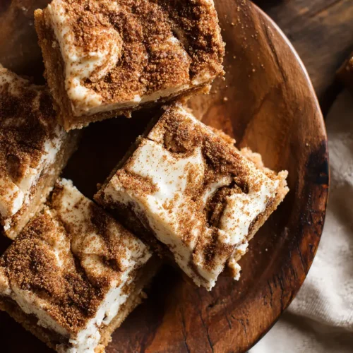 A close-up of a tray of freshly baked cinnamon roll bliss bars with white icing.