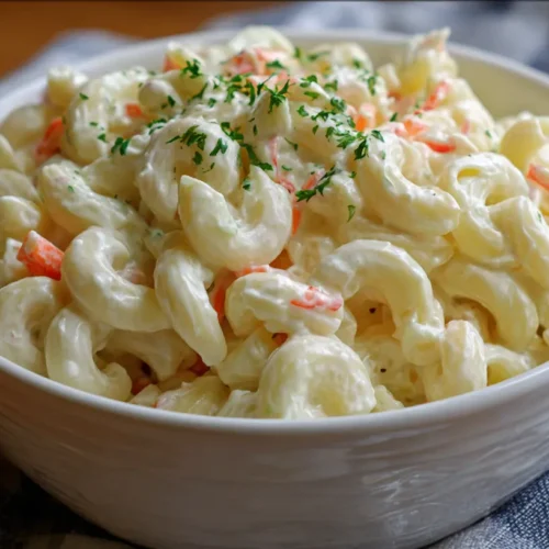 A bowl of creamy macaroni salad with vibrant vegetables.