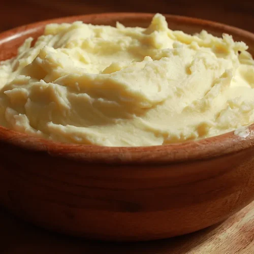 A bowl of creamy mashed potatoes garnished with herbs