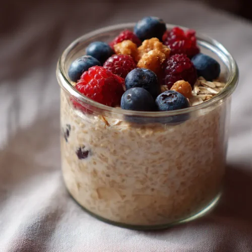 A glass jar filled with delicious overnight oats, topped with fresh berries