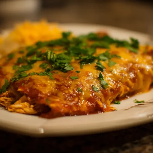 Platter of savory chicken or beef enchiladas topped with cheese and sauce.